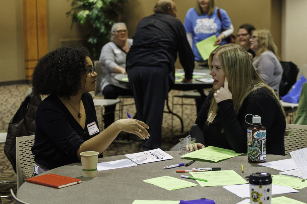 Two women speak to each other across a table at the 2023 IDEA Conference